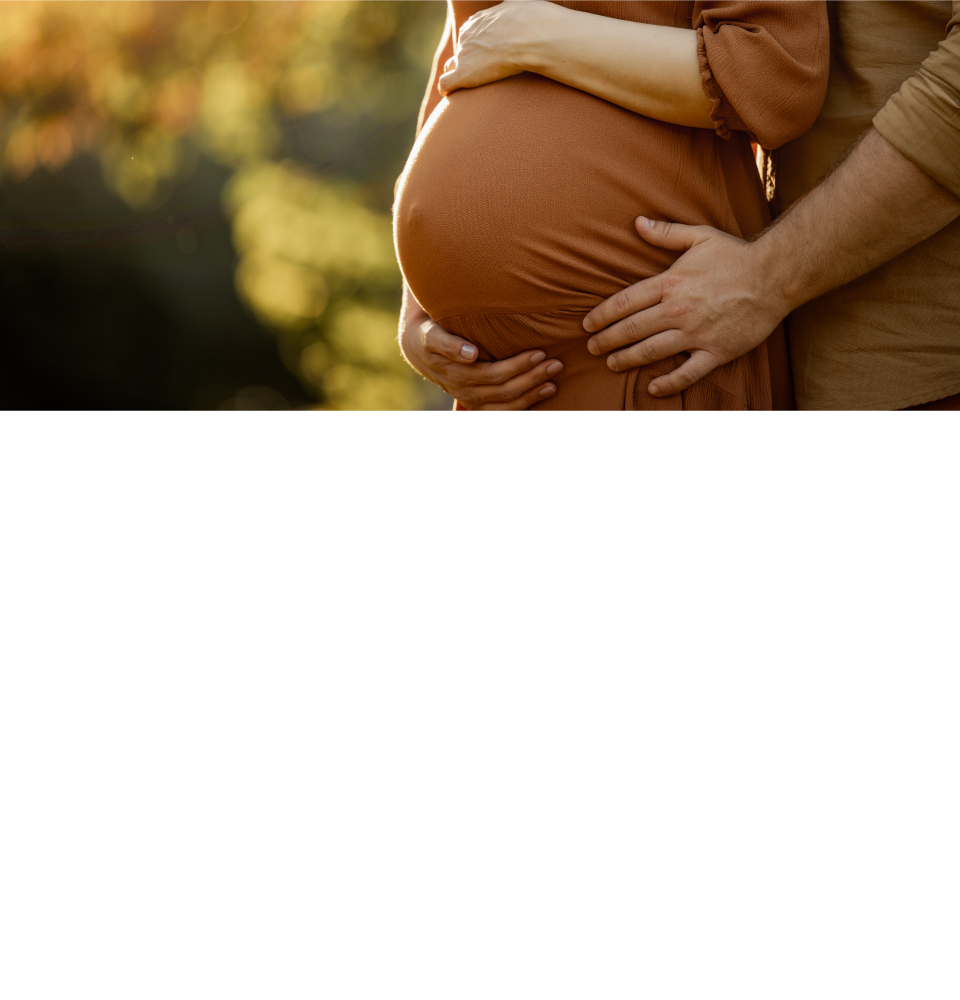 pregnant couple standing in the setting sun