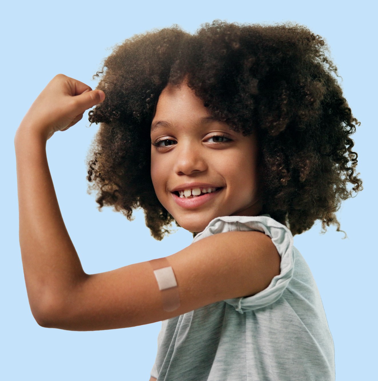 Smiling girl flexing her arm with a bandage after her flu shot
