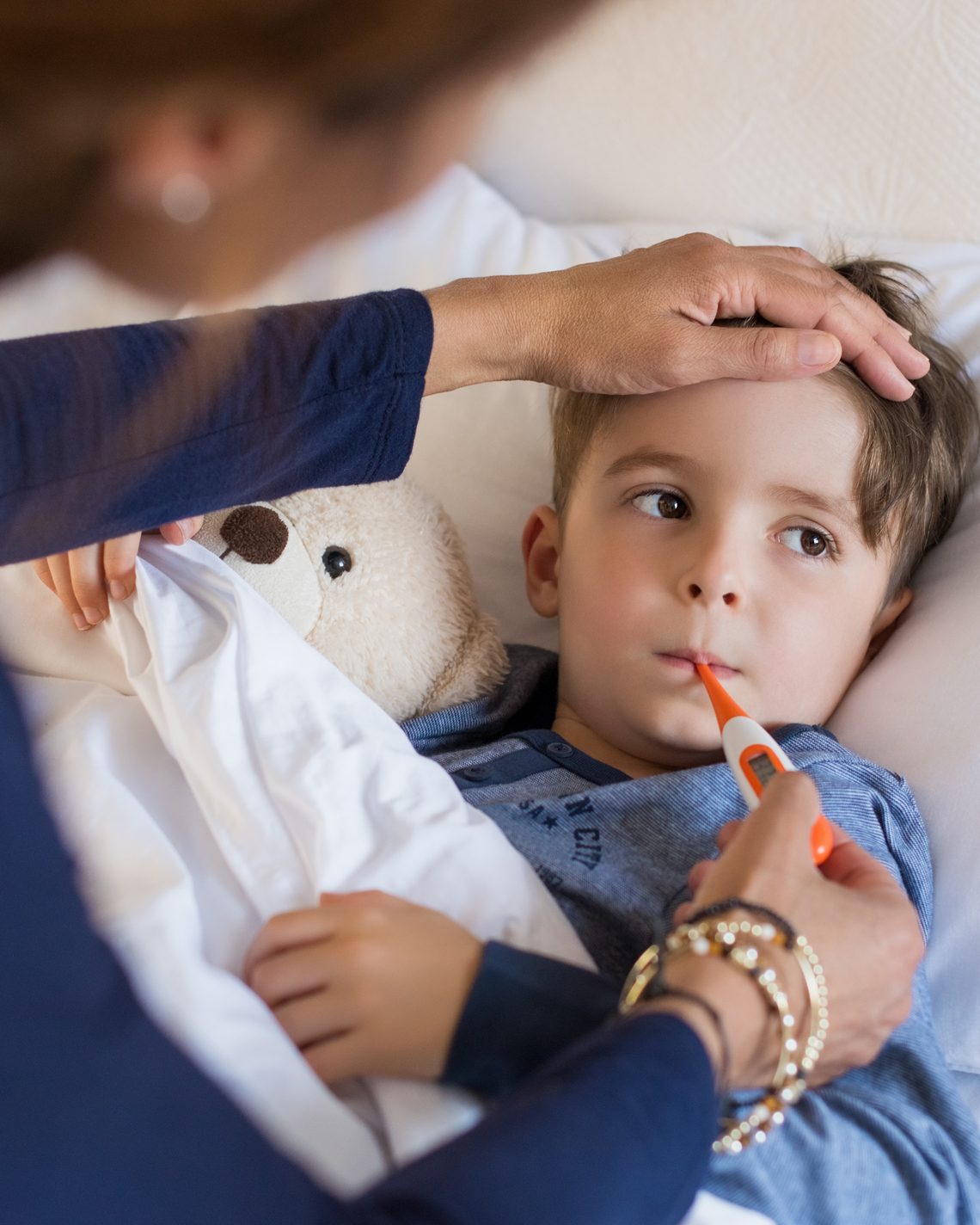 Mother checking her son's temperature with a thermometer